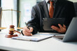 © laddawan - justice and law concept.Male judge in a courtroom  the gavel, working with tablet on table .