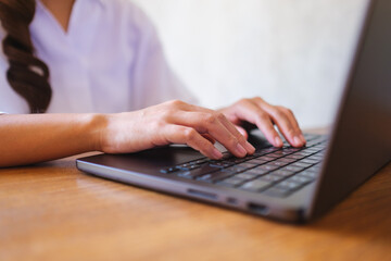 Wall Mural - closeup image of a woman working and typing on laptop computer keyboard