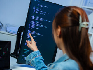 professional asian female software engineer looking at monitor screen, analyzing source code algorit