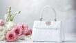 © Artittaya - A luxurious white handbag perfect for a wedding, displayed with floral decor.