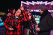 © qunica.com - Friends interacting and enjoying themselves outside during a winter evening with festive lights.