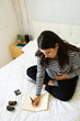 © AntonioDiaz - Top view of pregnant woman sitting on bed writing on notebook, touching her belly and looking at ultrasound scan of baby