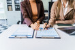 © Phushutter - Two female business professionals in suits sit at desk, engaged in strategic discussion. They analyze financial planning, risk management, corporate growth while reviewing reports and market trends.