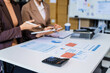 © Phushutter - Two female business professionals in suits sit at desk, engaged in strategic discussion. They analyze financial planning, risk management, corporate growth while reviewing reports and market trends.