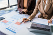© Phushutter - Two female business professionals in suits sit at desk, engaged in strategic discussion. They analyze financial planning, risk management, corporate growth while reviewing reports and market trends.