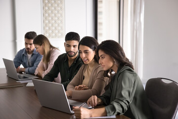 group of focused workmates looking at laptop screen, watching content related to their workflow, rev