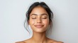 © QuietWord - pretty Indian woman with gentle smile with eyes close, clean clear facial skin, white background, all hair pull back