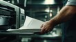 © yusufadi - High-Quality Printing: A Close-Up of a Man Carefully Handling Freshly Printed Papers from a Modern Printing Press, Showcasing the Precision and Detail Involved in the Printing Process.