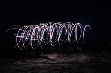 Wall Mural - Abstract circular light drawings captured in motion against a dark background