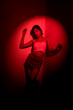 © Kaushik - Stylish Young Woman in Denim Skirt and Crop Top Shot Under Red Lighting Against Wall