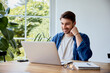 © baranq - Smiling young man working with laptop at home