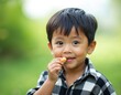 © Vadym - Portrait of cute 2 year old asian boy snacking, black hair, black eyes, green nature background. Kid eats in garden, looks at camera, childhood learning, happy family fun concept.