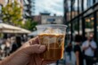 © Feel Fine - Close-up view of a barista serving iced coffee at a bustling outdoor cafe during a sunny afternoon
