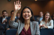© Vadym - Young smiling businesswoman raises hand at conference. Asian woman asks question during presentation in audience. Professional raises arm during business meeting, seminar, lecture. Participation,