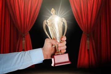 Wall Mural - man holding golden trophy on stage, closeup