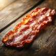 © Faizal - Crispy bacon slice atop rustic wooden surface enhanced by warm light in delicious food photography close up
