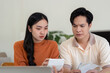 © Natee Meepian - Couple Financial Planning. Concerned couple reviewing finances with receipts and calculator.