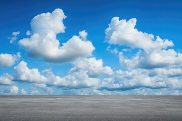 empty asphalt surface under a vibrant blue sky with fluffy white clouds