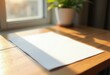 © Анжелика Лещенко - A4 paper mockup on wooden desk with sunlight and plant.
