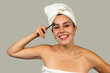 © EDUARDOIVAN - Smiling woman combing eyebrows after shower wearing towel turban