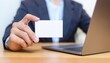 © photostockatinat - business person holding a blank business card in front of a laptop