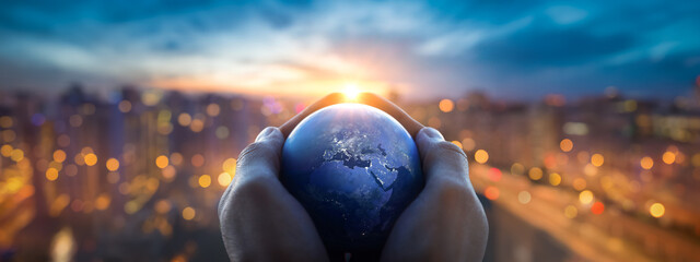 Wall Mural - the globe earth in the hands of man against the night city. earth day abstract background. elements 