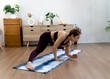 © sabthai - Asian woman in her 50s warms up on a yoga mat on the floor before starting