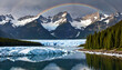 © SolarisKG - Le paysage majestueux d'un lac gelé entouré de montagnes enneigées avec un arc-en-ciel au-dessus.