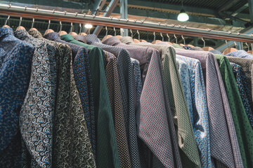 Poster - A rack of colorful shirts in a store. The shirts are arranged in a rainbow order, from light to dark. The display is eye-catching and inviting, drawing the attention of potential customers