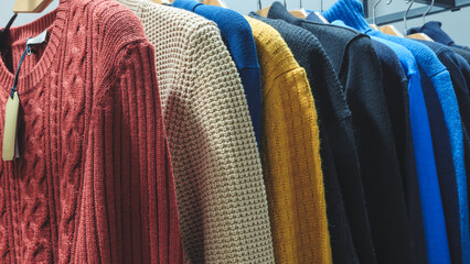 Poster - A rack of sweaters with a tag on the red one. The sweaters are of different colors and styles