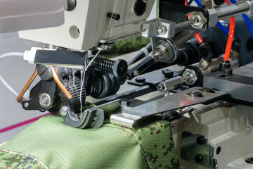 Poster - A sewing machine is in use, with a green fabric being sewn. The machine has a black and silver color scheme