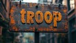 © aicandy - Aged Wooden Sign Bearing the Word 'Troop' in Rustic Bold Yellow Letters Highlighted Against a Blurred Urban Background Exuding Vintage Charm and Mystery