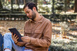 © Brand - Young man reading e book on tablet in park with bad posture