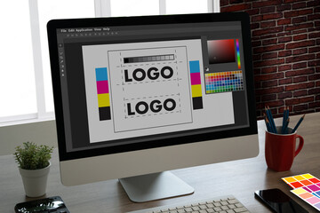 graphic designer using a tablet and computer to create a brand logo with a colour palette in illustr