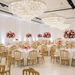 © Shavy - elegant white and gold wedding reception decor with chandeliers and floral centerpieces in a large hall