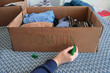 © SKfoto - A man signs a cardboard donation box with a green marker.