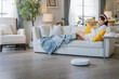 © whyframeshot - Young Asian woman relaxing sit on sofa home and turning on her smart vacuum cleaner using smartphone control robot while listening music headphone smart life smart technology lifestyle home hygiene