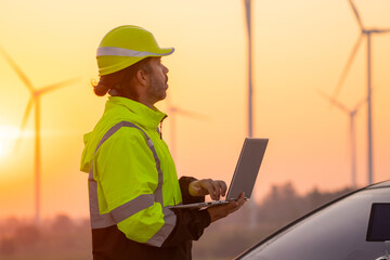 Aufkleber - Engineer working on laptop in front of wind turbines for checking wind turbines of the field during beautiful sunset. Alternative energy concept.