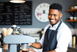 © Leonardo - Hombre barista afroamericano atractivo que viste un delantal y prepara café en una cafetería