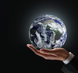 planet in our hands. man holding glowing earth on black background, closeup