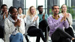 © Katsiaryna - Selective focus of young businesswoman applauding together with interracial colleagues during seminar