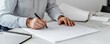 © ParinApril - Focused Designer Sketching Architectural Plans on a Spacious Table with Paper and Tools Nearby