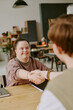 © AnnaStills - Vertical shot of young applicant with down syndrome shaking hands with male job interviewer