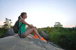 © bilanol - Hiker girl resting on rocky mountain top enjoying morning nature during her travel on wilderness trail. Lonely female traveler traversing high hilltop route. Healthy lifestyle concept