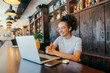 © Dusan Petkovic - Portrait of smiling girl sitting in cafeteria and having conference call on laptop with colleagues remotely.