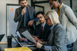 © La Famiglia - Focused executives analyzing data on a laptop in a well-lit boardroom