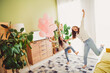 © deagreez - Joyful mother and daughter dancing in living room filled with sunlight and balloons on a cheerful weekend morning