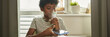 © pressmaster - Header of youthful African American schoolboy holding smartphone over copybook and inhaling vapors from nebulizer mask on his nose