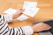 © New Africa - Paying bills. Woman with different invoices and laptop at wooden table indoors, closeup