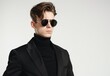 © PUTRI - Serious body guard or secret agent wearing suit and sunglasses, isolated on grey background